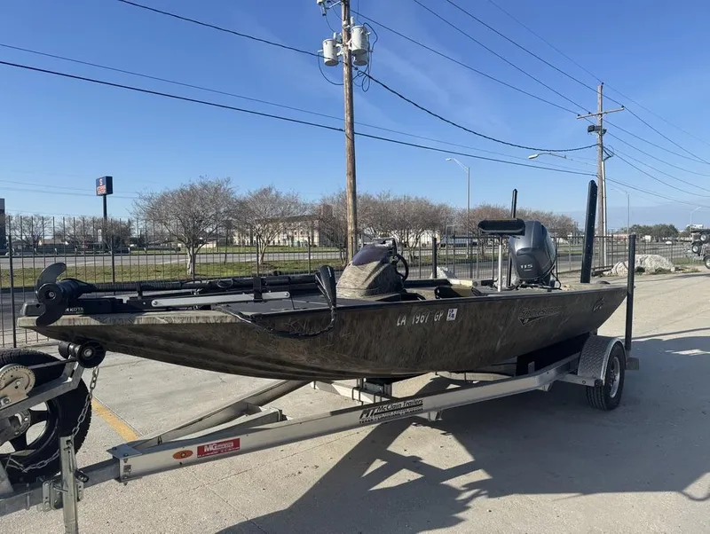 Slide: The Image of 2018 G3 Sportsman 18 Camo boat on trailer, parked outdoors under clear blue sky. - 13