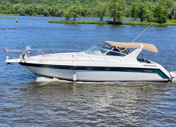 Slide: The Image of 1994 Regal Commodore 400 boat cruising on a scenic river with lush green trees. - 2