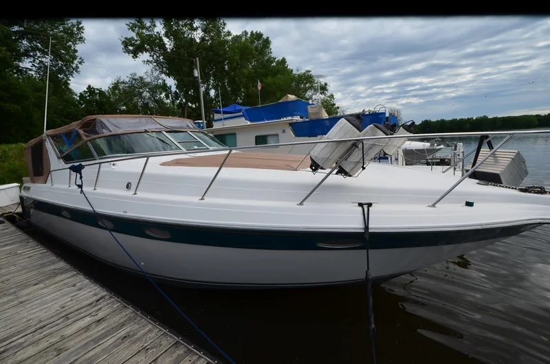 Slide: The Image of 1994 Regal Commodore 400 boat docked by a serene lake under cloudy skies. - 7