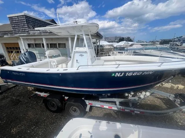 Slide: The Image of 2004 Regulator 24 Forward Seating boat on trailer, parked outdoors under blue sky. - 1