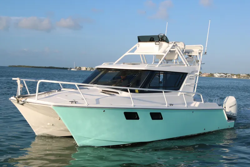 Slide: The Image of 2020 ArrowCat 320 Fly Dual Helm boat on calm water, featuring sleek design and turquoise hull. - 0