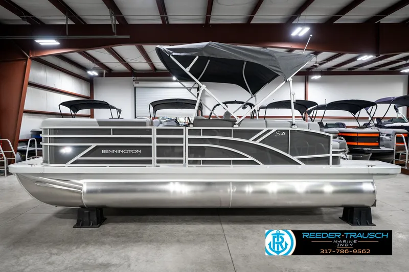 Slide: The Image of 2025 Bennington 21 SLJ pontoon boat in showroom, featuring sleek design and canopy. - 11