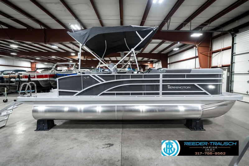 Slide: The Image of 2025 Bennington 21 SLJ pontoon boat in showroom, featuring sleek design and canopy. - 7