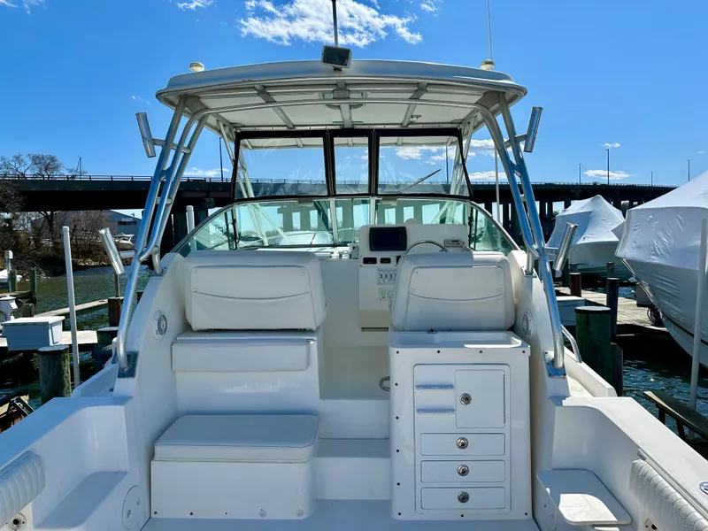 Slide: The Image of 2005 Stamas 320 Express boat interior with seating and storage, docked under clear blue sky. - 15