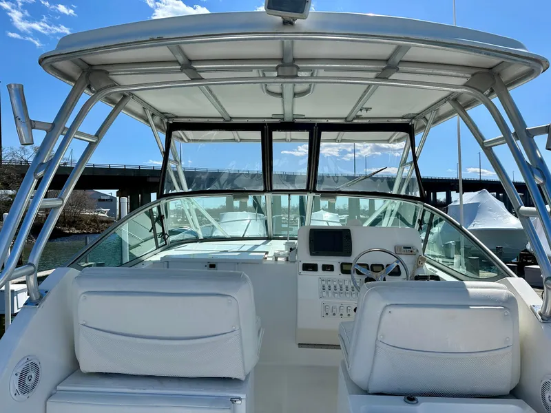 Slide: The Image of 2005 Stamas 320 Express boat cockpit with helm, white seating, and clear windshield. - 19