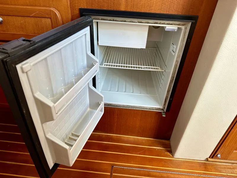 Slide: The Image of Open mini fridge inside 2005 Stamas 320 Express boat, showing empty shelves and door compartments. - 35