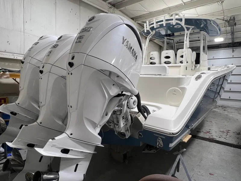 Slide: The Image of 2025 Cobia 350 Center Console boat with triple Yamaha outboard engines in a garage. - 2