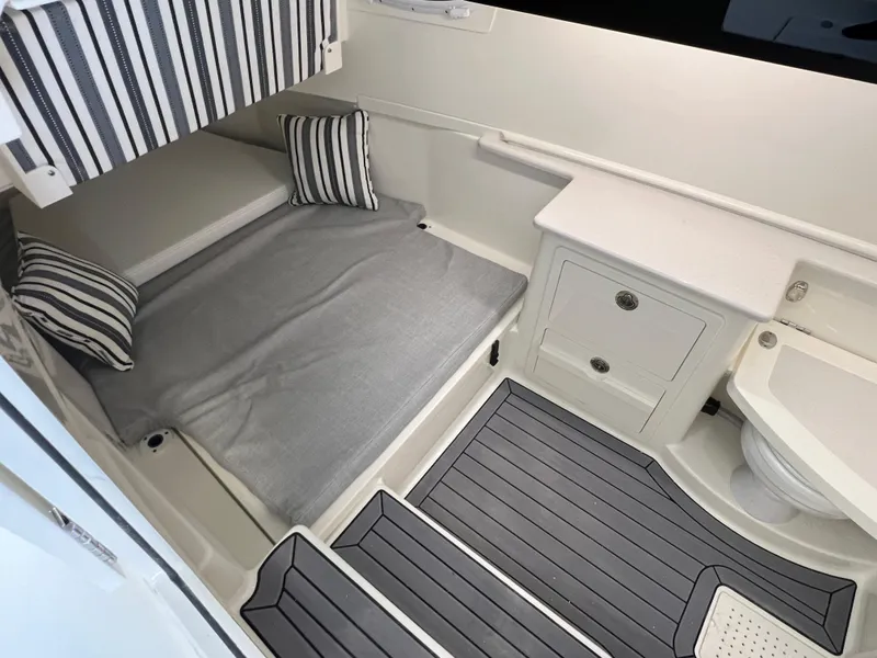 Slide: The Image of 2025 Cobia 350 Center Console cabin with bed, striped pillows, and compact bathroom. - 23
