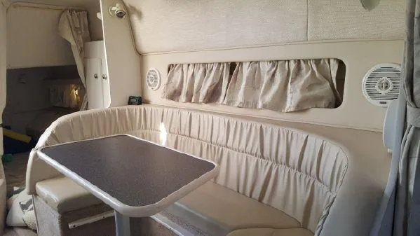 Slide: The Image of 1998 Rinker Fiesta Vee 280EC cabin interior with dining area and beige seating. - 12