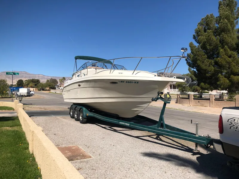 Slide: The Image of 1998 Rinker Fiesta Vee 280EC boat on trailer, parked on a sunny street. - 6