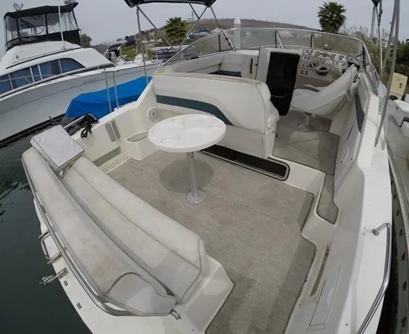 Slide: The Image of 1998 Rinker Fiesta Vee 280EC boat interior with seating and table, docked at marina. - 8
