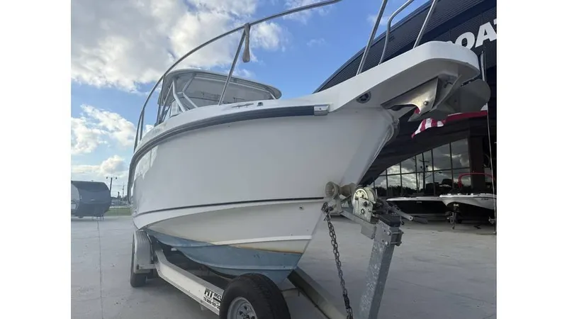Slide: The Image of 2006 Boston Whaler 285 Conquest boat on trailer, parked outdoors under a partly cloudy sky. - 11