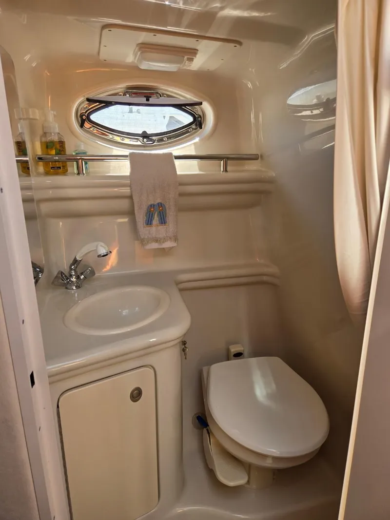 Slide: The Image of 2006 Sea Ray 270 Amberjack bathroom with sink, toilet, and porthole window. - 12