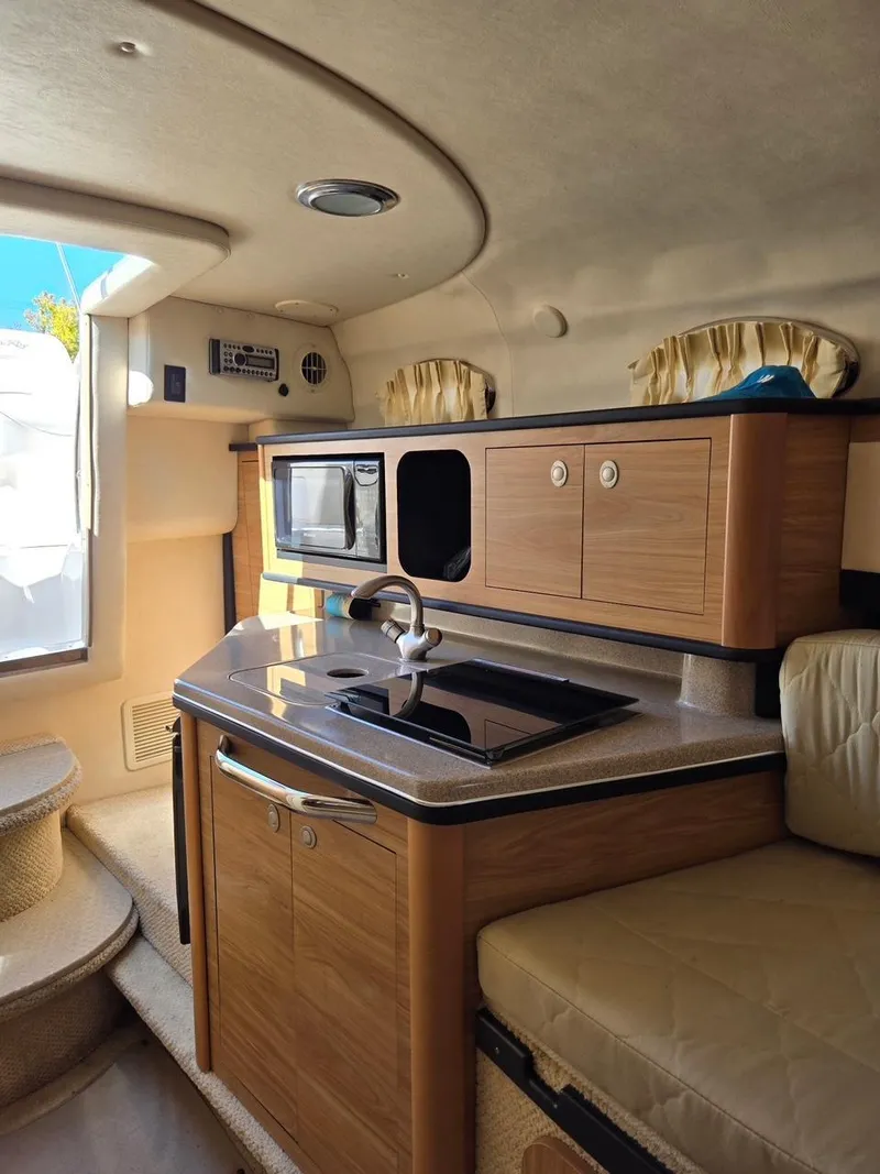 Slide: The Image of 2006 Sea Ray 270 Amberjack interior with kitchenette, microwave, and seating area. - 13