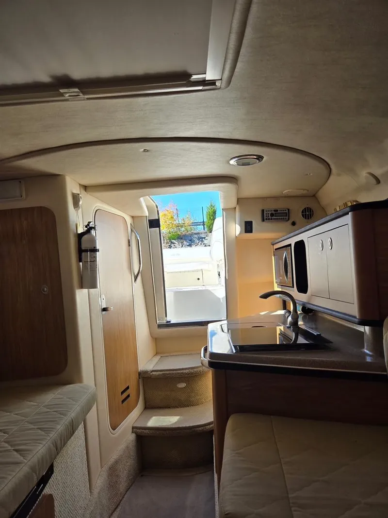 Slide: The Image of Interior of a 2006 Sea Ray 270 Amberjack boat, featuring a compact kitchen and seating area. - 14