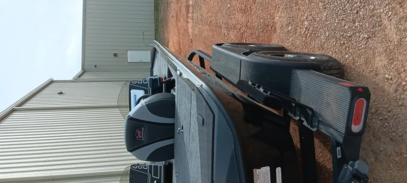 Slide: The Image of 2025 Ranger ALPHA 208 boat on trailer, parked on gravel near a metal building. - 11