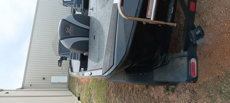 Slide: The Image of 2025 Ranger ALPHA 208 boat on trailer, parked near a building. - 12