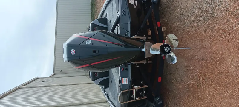 Slide: The Image of 2025 Ranger ALPHA 208 boat with powerful outboard motor and propeller, parked on gravel. - 13