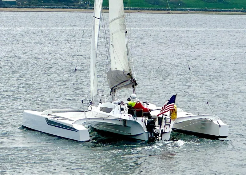 Slide: The Image of 2021 Dragonfly 25 Touring trimaran sailing on calm waters with American flag. - 2