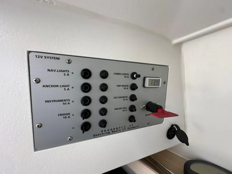 Slide: The Image of Control panel of a 2021 Dragonfly 25 Touring boat, featuring various switches and a digital display. - 48