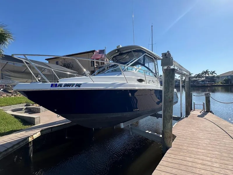 Slide: The Image of 2012 Robalo R265 Walkaround boat docked in sunny marina setting. - 1