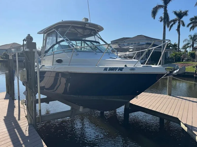 Slide: The Image of 2012 Robalo R265 Walkaround boat docked near waterfront homes and palm trees. - 2