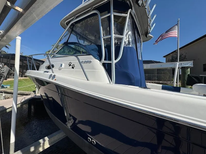 Slide: The Image of 2012 Robalo R265 Walkaround boat docked, featuring sleek design and American flag in background. - 4