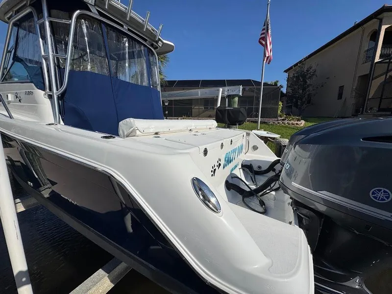 Slide: The Image of 2012 Robalo R265 Walkaround boat with Yamaha engine, docked near a house and American flag. - 5
