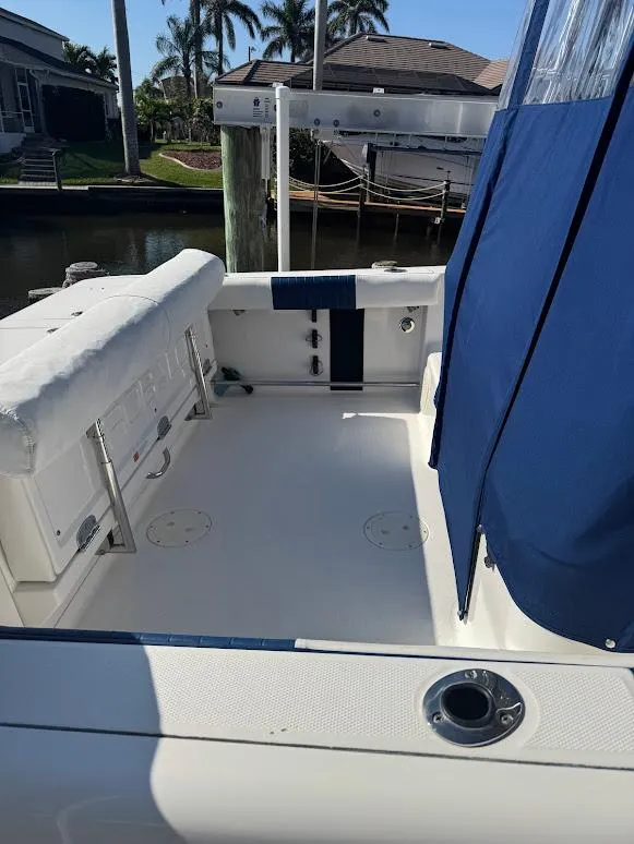 Slide: The Image of 2012 Robalo R265 Walkaround boat deck with blue canopy, docked near waterfront homes. - 8