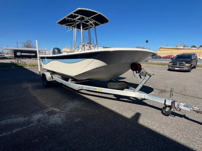 Slide: The Image of 2016 Carolina Skiff 198 DLV boat on trailer, parked outdoors under clear blue sky. - 10