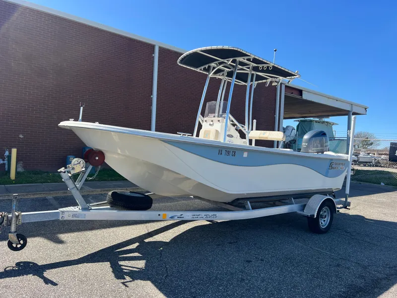 Slide: The Image of 2016 Carolina Skiff 198 DLV boat on trailer, parked outdoors, clear sky background. - 2