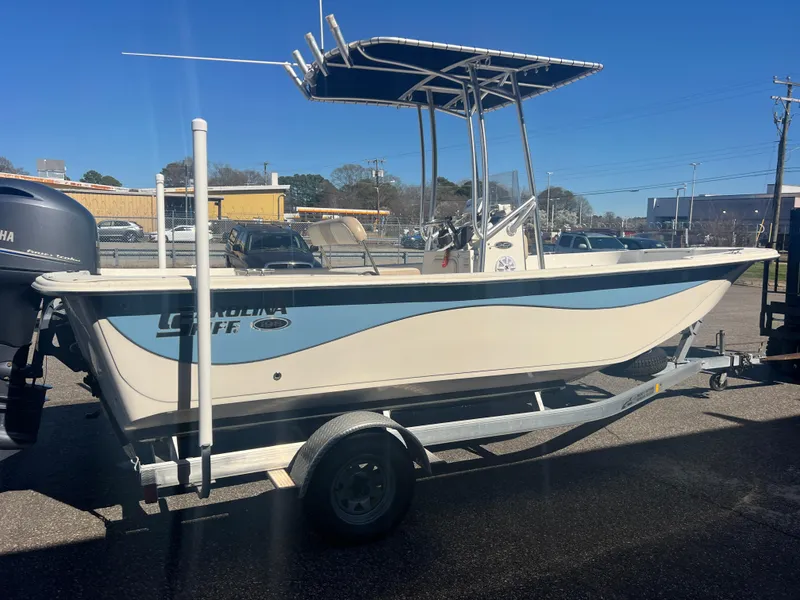Slide: The Image of 2016 Carolina Skiff 198 DLV boat on trailer, parked outdoors under clear blue sky. - 8
