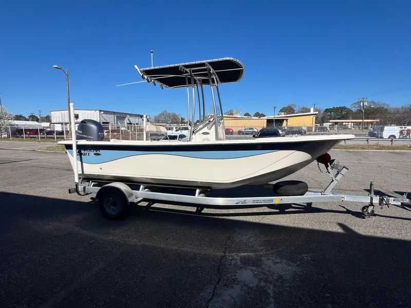 Slide: The Image of 2016 Carolina Skiff 198 DLV boat on trailer, parked outdoors under clear blue sky. - 9