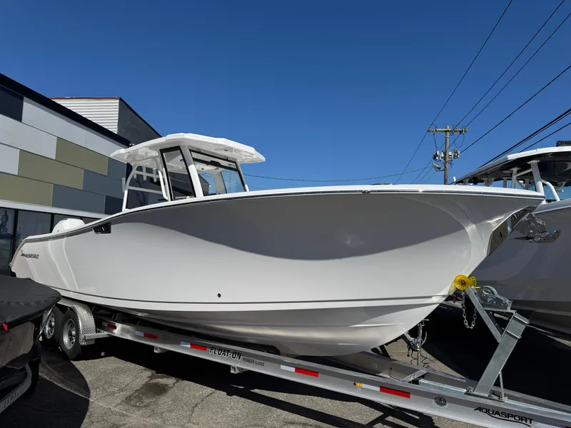 Slide: The Image of 2025 Aquasport 28AS Center Console boat on trailer, parked outdoors under clear blue sky. - 0