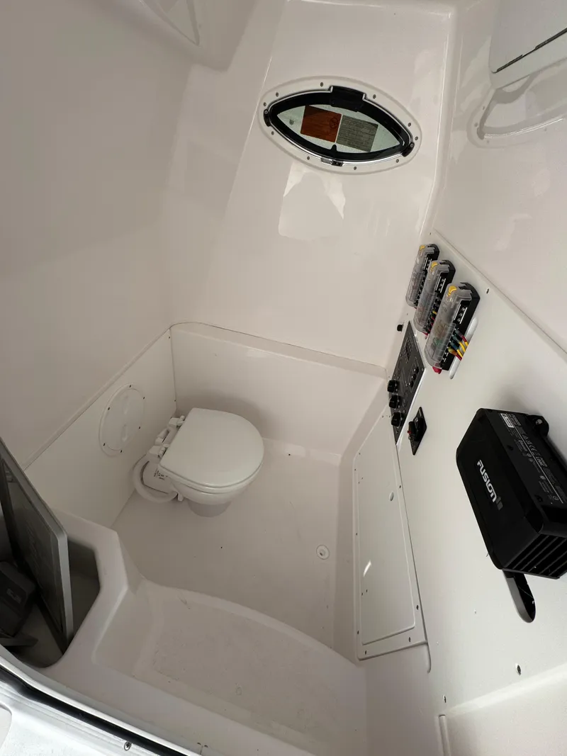 Slide: The Image of 2025 Aquasport 28AS Center Console interior with toilet and control panel. - 16