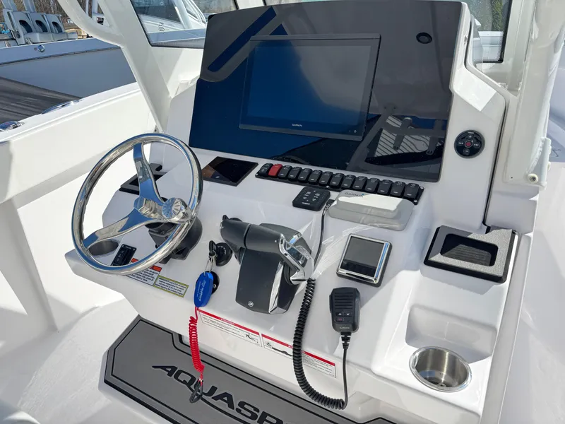 Slide: The Image of 2025 Aquasport 28AS Center Console boat dashboard with steering wheel and electronic controls. - 5