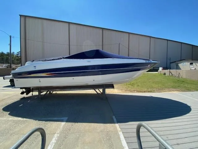 Slide: The Image of 2005 Bayliner 249 SD boat on trailer, parked outdoors near a large building. - 14