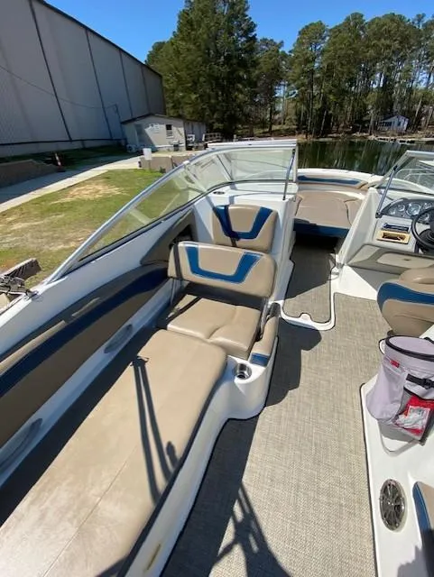 Slide: The Image of 2005 Bayliner 249 SD boat interior with beige seating and clear windshield, docked near trees. - 9