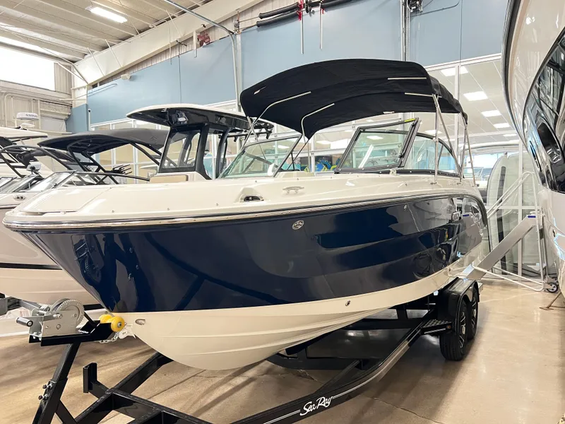 The Image of 2025 Sea Ray SDX 250 boat in showroom, blue and white exterior, on trailer. - 0