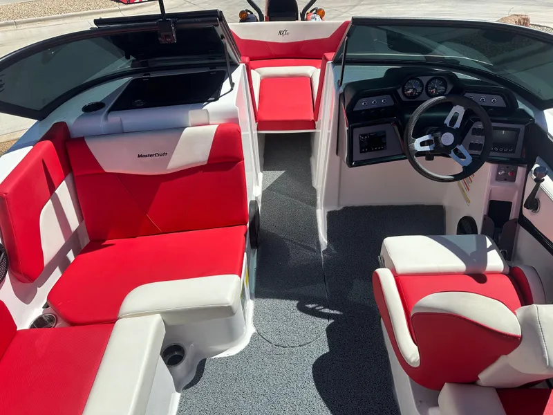 Slide: The Image of 2023 MasterCraft NXT22 boat interior with red and white seating, modern dashboard, and steering wheel. - 10