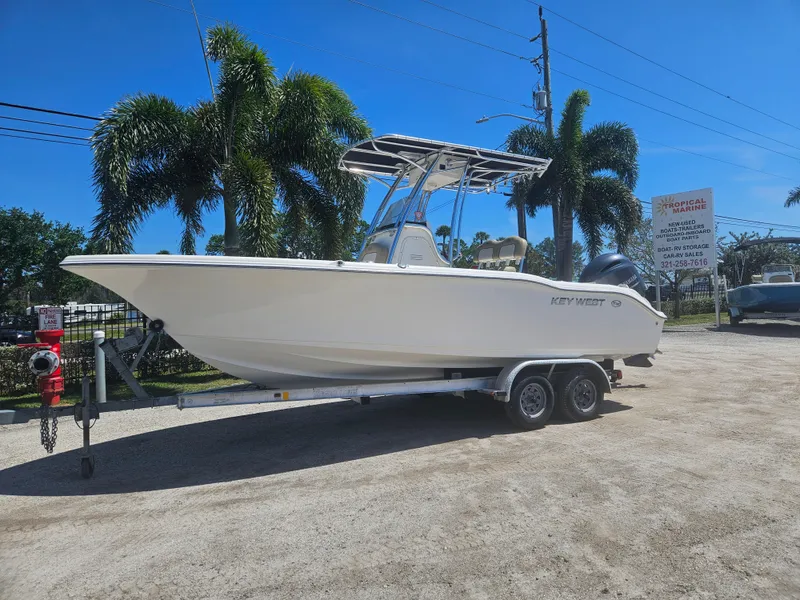 The Image of 2018 Key West 219 FS boat on trailer, parked outdoors with palm trees in background. - 1