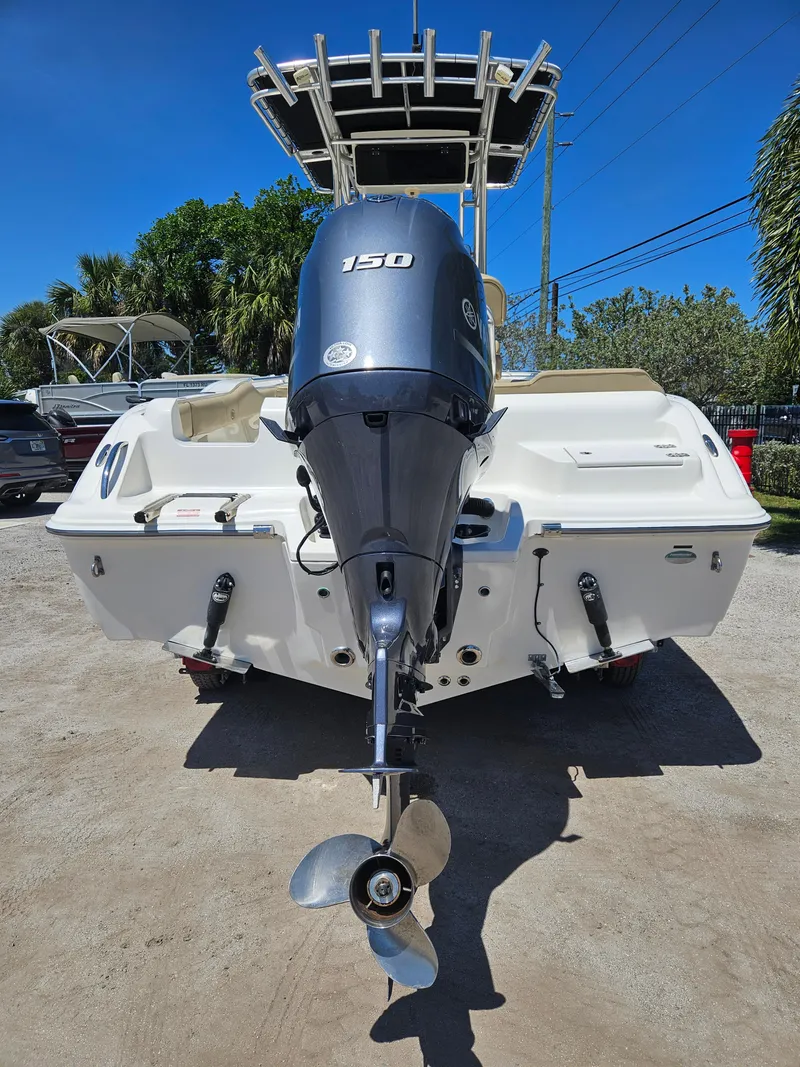 Slide: The Image of 2018 Key West 219 FS boat with 150 HP outboard motor, parked outdoors. - 18