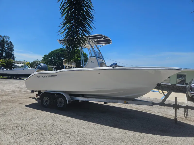 Slide: The Image of 2018 Key West 219 FS boat on trailer, parked outdoors under clear blue sky. - 4