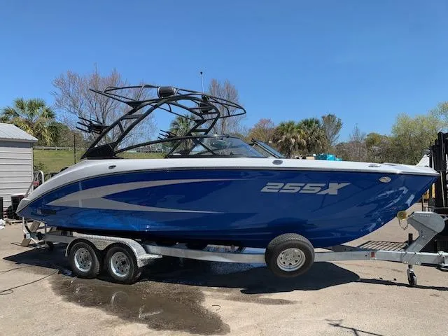The Image of 2025 Yamaha Boats 255XD, blue and white, on a trailer, parked outdoors. - 0