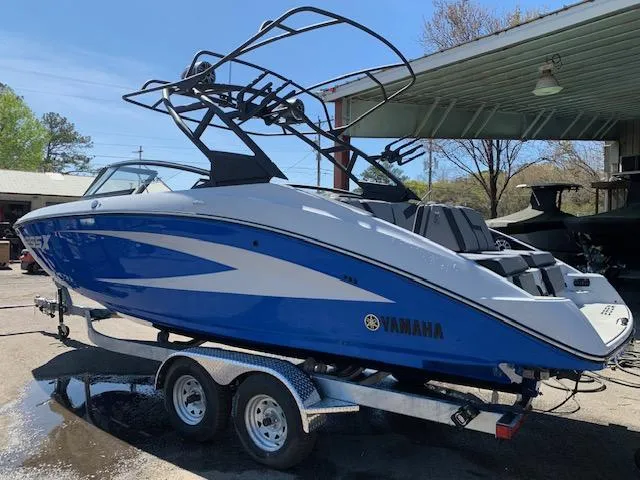 Slide: The Image of 2025 Yamaha Boats 255XD in blue on a trailer, parked outdoors. - 1