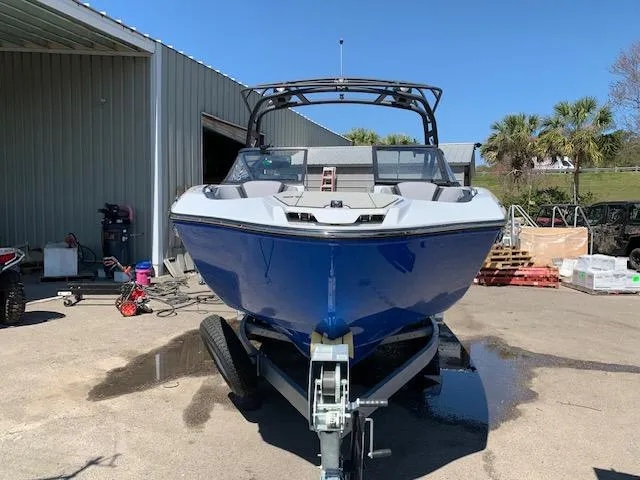 Slide: The Image of 2025 Yamaha Boats 255XD in blue, parked on a trailer outside a warehouse. - 15