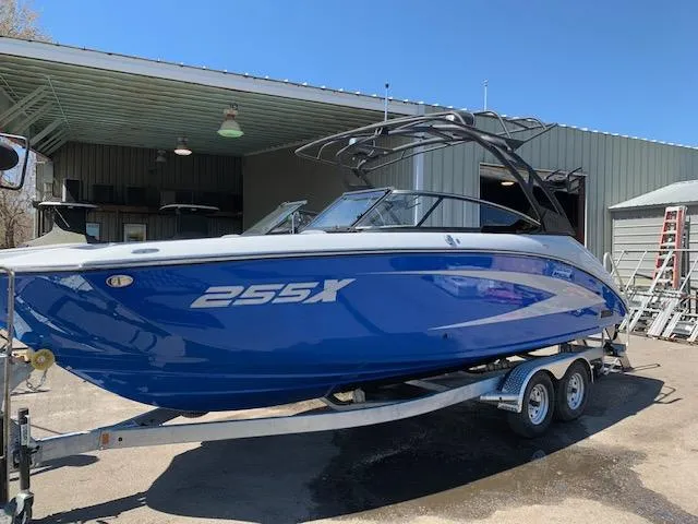 Slide: The Image of 2025 Yamaha Boats 255XD in blue on a trailer outside a warehouse. - 2