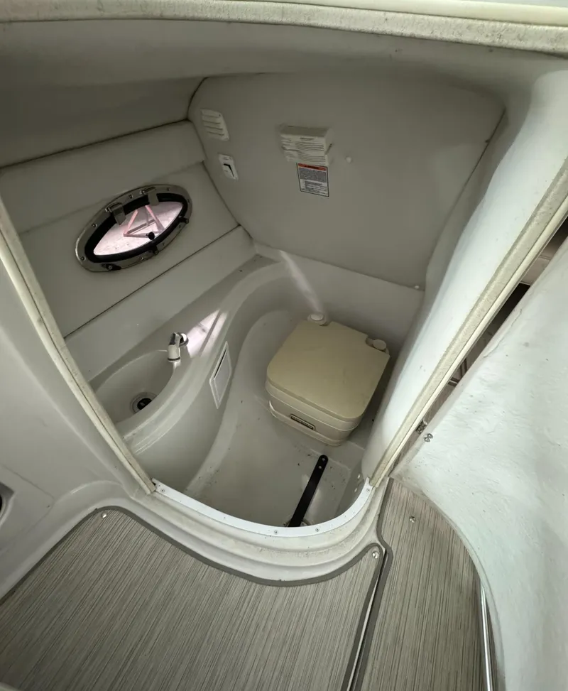 Slide: The Image of 2005 Crownline 240 EX boat interior with compact bathroom and porthole window. - 12