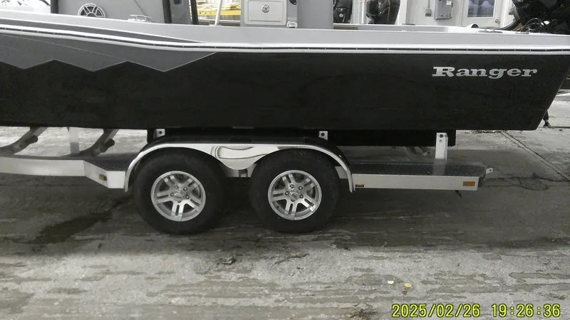 Slide: The Image of 2024 Ranger 2510 Bay boat on a dual-axle trailer in a garage setting. - 8