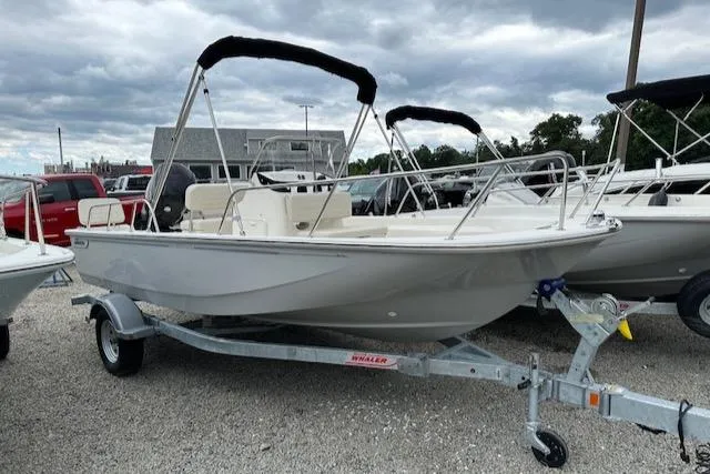 Slide: The Image of 2023 Boston Whaler 170 Montauk boat on trailer, parked outdoors under cloudy sky. - 0